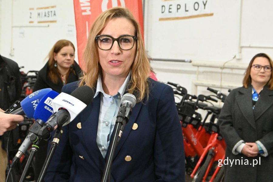 Kobieta mówiąca do kilku ustawionych obok siebie mikrofonów
