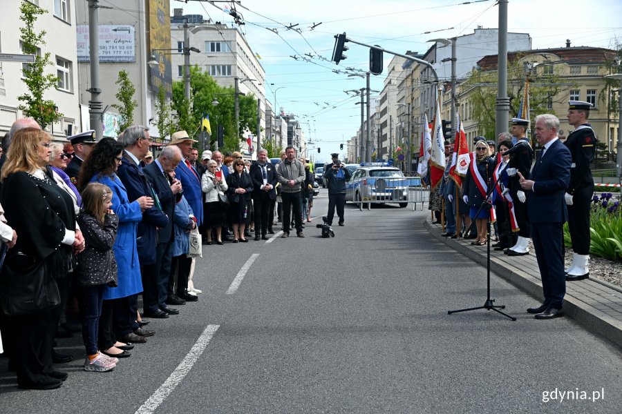 Podczas uroczystości głos zabrał senator Sławomir Rybicki (przy mikrofonie, po prawej). Za nim posterunek honorowy przy tablicy z nazwą węzła oraz poczty sztandarowe biorące udział w uroczystości // fot. Magdalena Czernek