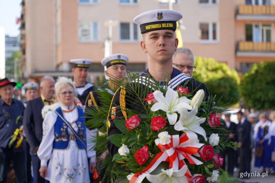 Kwiaty składa dr Wojciech Wosek, wiązankę niesie marynarz 