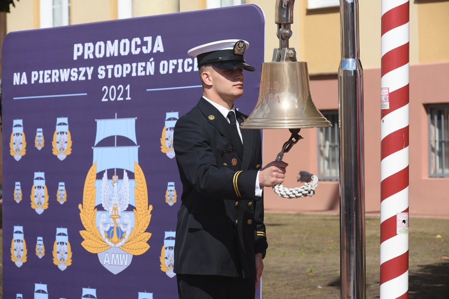 Młody żołnierz stoi przed dzwonem i wybija szklanki podczas uroczystej promocji oficerskiej w Akademii Marynarki Wojennej w Gdyni // fot. Krzysztof Miłosz