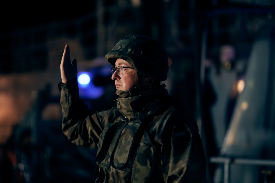 Żołnierz w mundurze moro stoi z uniesioną ręką. Pada na niego snop światła // fot. Michał Pietrzak / 3. Flotylla Okrętów 