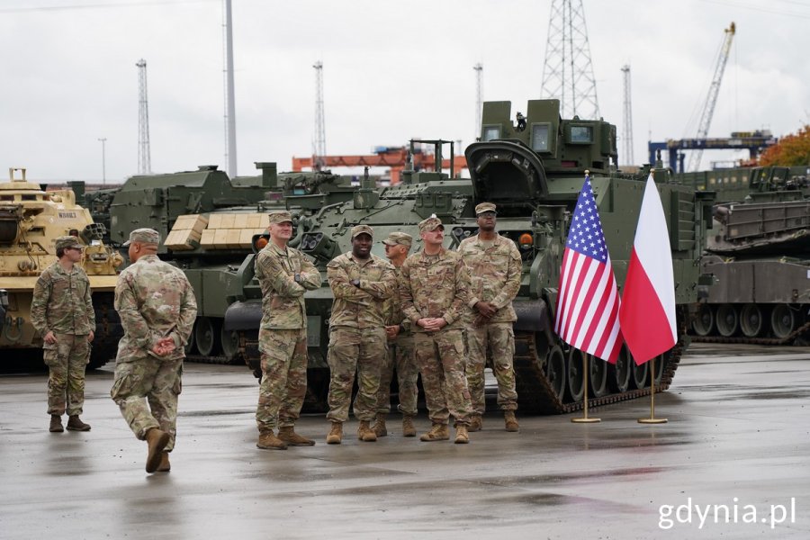 Żołnierze z 598. Brygady Transportowej US Armym obok pojazdy wojskowe i flagi: Polski i USA
