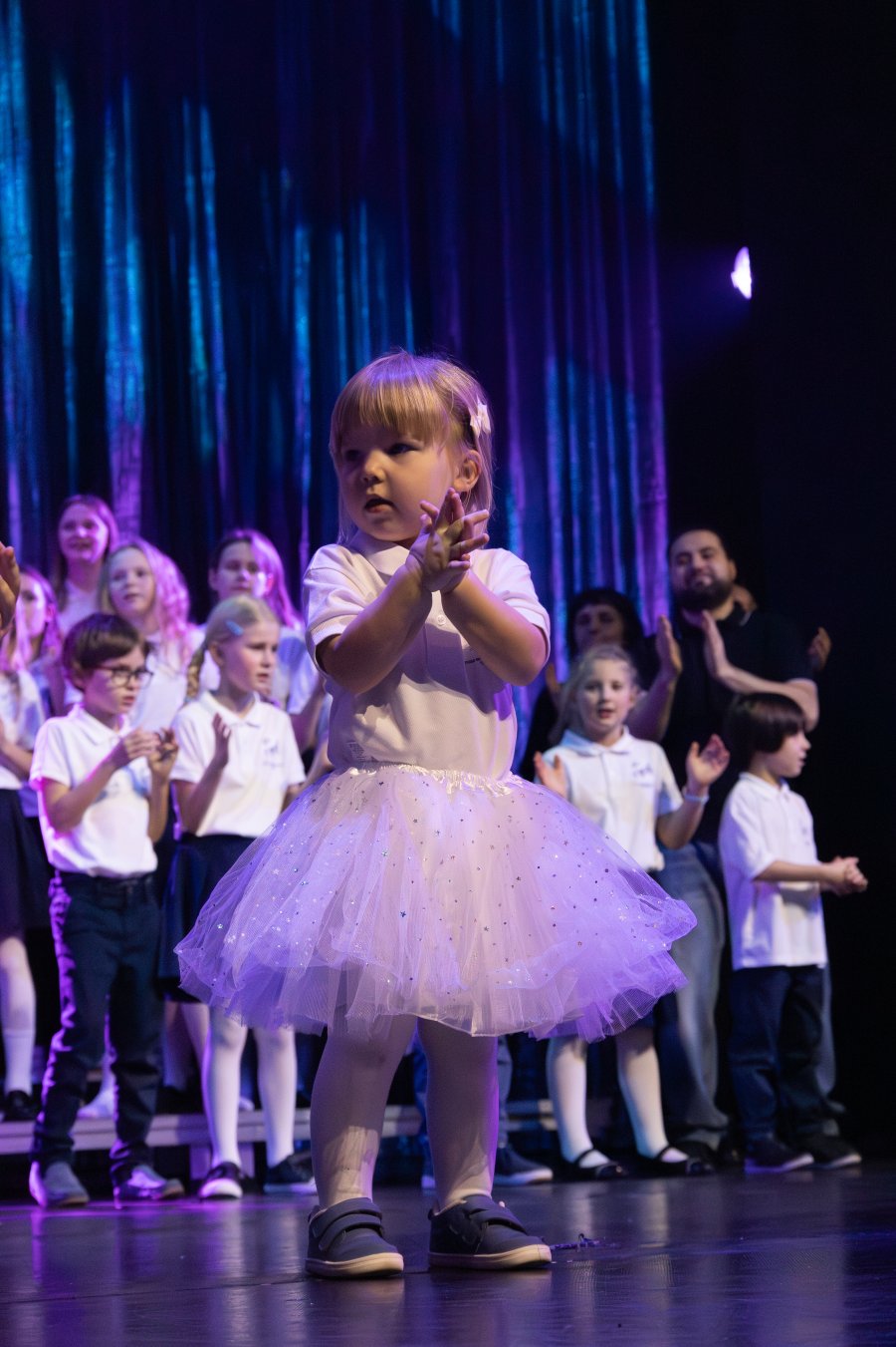 Mała dziewczynka w białym stroju na scenie