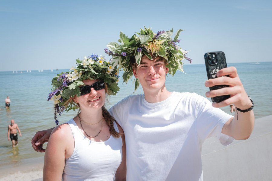 Para młodych os&oacute;b robiąca selfie, mają wianki na głowie z kwiat&oacute;w i liści