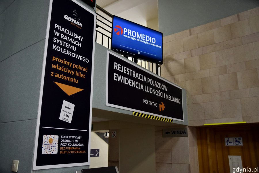 Tablice informujące o tym, że urząd działa w ramach systemu kolejowego i należy pobrać bilet z automatu, aby załatwić sprawę // fot. Paweł Kukla