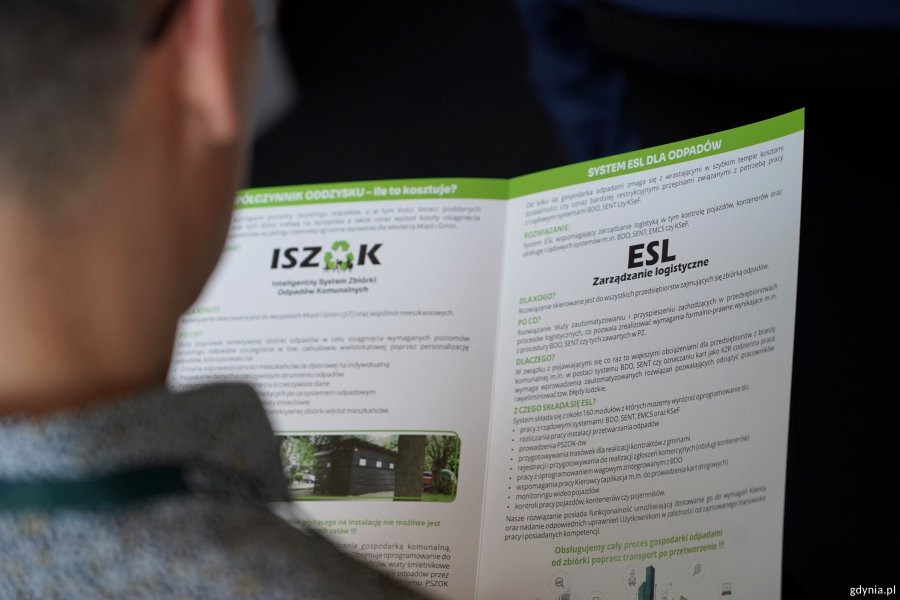 Osoba czyta ulotkę o systemie dla odpad&oacute;w