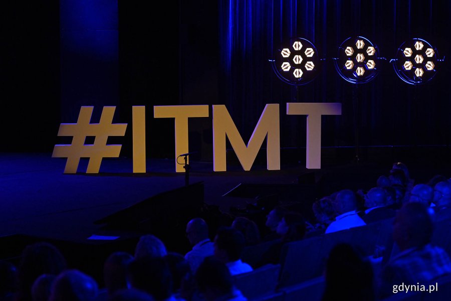 Hashtag konferencji „IT Manager of Tomorrow” na scenie Teatru Muzycznego. Za nim - trzy lampy w kształcie plastra miodu // fot. Michał Puszczewicz