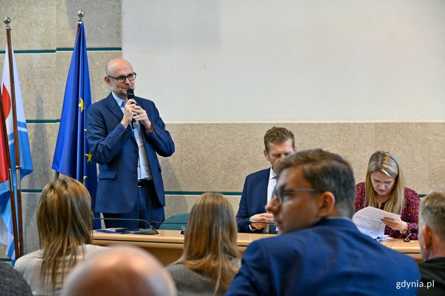 Przy mikrofonie wiceprezydent Gdyni Bartłomiej Austen oraz uczestnicy spotkania w sali obrad Urzędu Miasta Gdyni