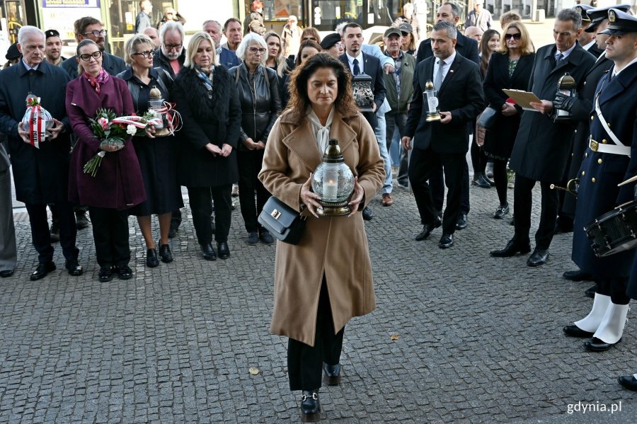 Posłanka Dorota Arciszewska-Mielewczyk składająca znicz pod tablicą pamiątkową, kt&oacute;ra znajduje się na fasadzie Dworca PKP Gdynia Gł&oacute;wna, podczas uroczystości z okazji 87. rocznicy pierwszych wysiedleń Gdynian 