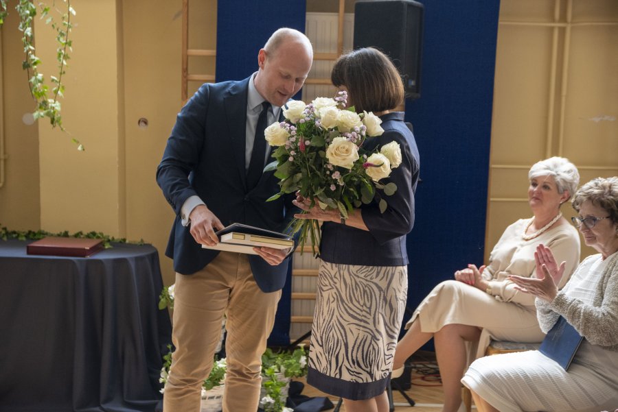 Tradycyjne kwiaty i życzenia od wiceprezydenta Bartoszewicza na ręcę dyrektor szkoły. Twarz pani dyrektor zasłania bukiet