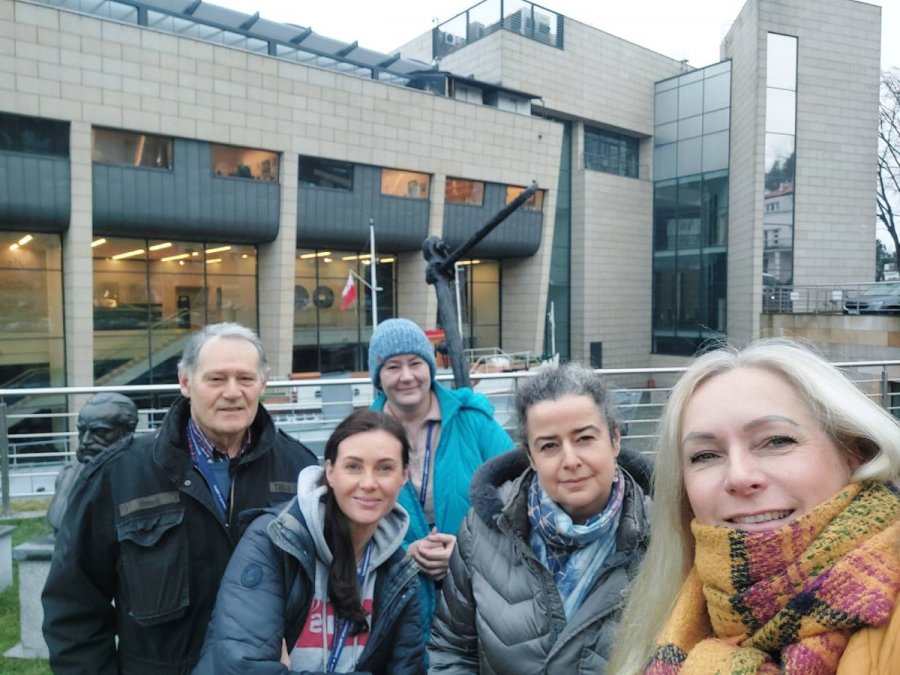 Kobiety i mężczyzna na tle beżowo-szarego budynku muzeum