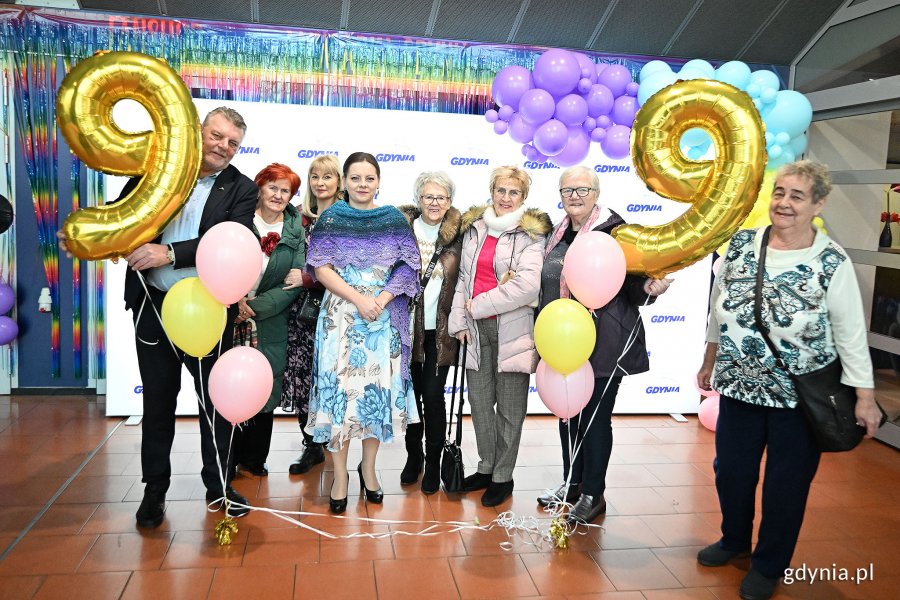 Hala Polsat Plus Arena, prezydent Aleksandra Kosiorek i grupa seniorów pozują do zdjęcia, w tle logotypy Gdyni, balony "99"