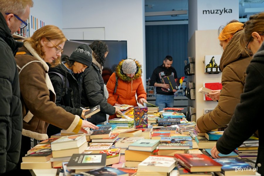 Uczestnicy charytatywnego kiermaszu w Bibliotece Śr&oacute;dmieście podczas przeglądania książek  