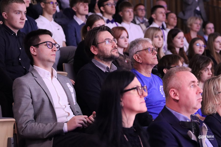 Mężczyźni i kobiety siedzący na krzesłach w auli
