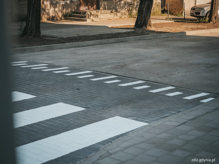 na pierwszym planie widoczne przejście dla pieszych, oznakowane poziomo
