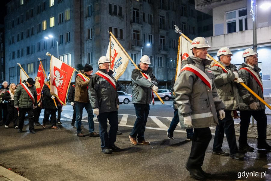 Pochód ludzi ze sztandarami idący ulicami miasta