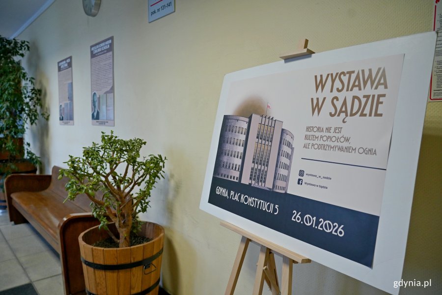 Tablica informująca o wystawie w sądzie ustawiona na korytarzu sądowym