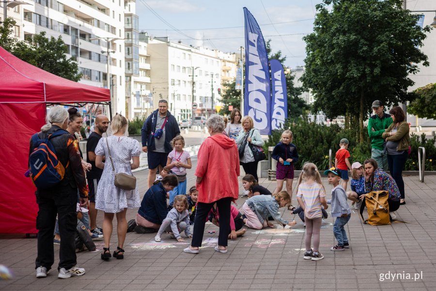 Dzieci rysują kredą na chodniku.