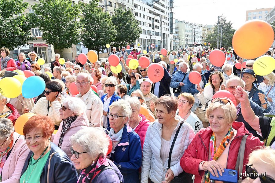 Uczestnicy przemarszu w ramach V Pomorskiego Dnia Seniora stojący na placu Kaszubskim. W rękach trzymają kolorowe balony