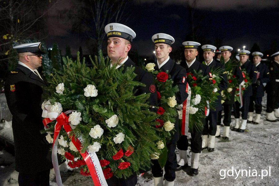 Ustawieni w rzędzie marynarze trzymający wieńce i wiązanki kwiatów podczas capstrzyku z okazji 105. rocznicy utworzenia Marynarki Wojennej 