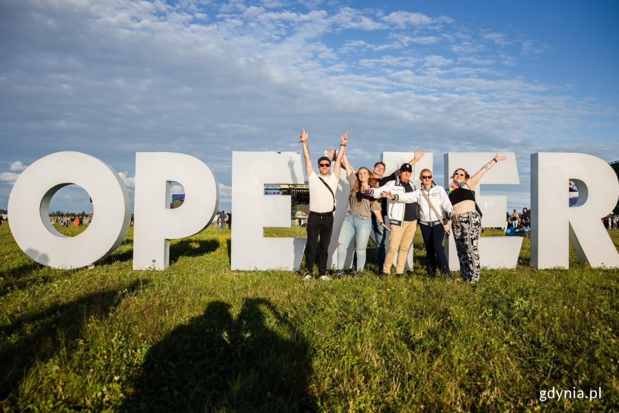 Uczestnicy festiwalu robiący zdjęcia przy znaku Open'era