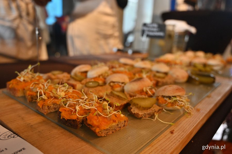 kanapki z kiełkami, ogórkiem, pastami, ułożone na drewnianej desce, pieczywo z ziarnami