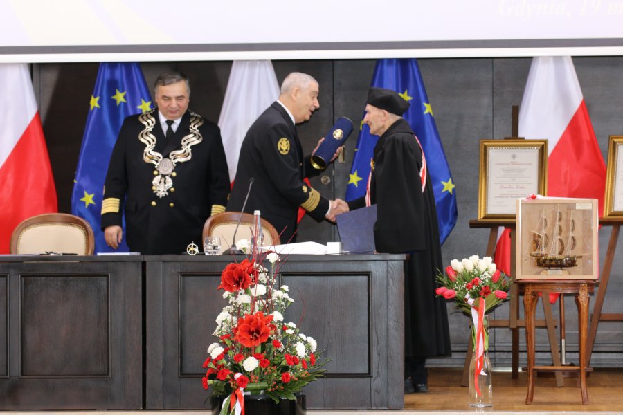 Prof. Piotr Jędrzejowicz gratuluje prof. Danielowi Dudzie tytułu doktora honoris causa. Po ich lewej stronie stoi prof. dr hab. inż. kpt. ż. w. Adam Weintritt - rektor Uniwersytetu Morskiego w Gdyni // fot. Uniwersytet Morski w Gdyni