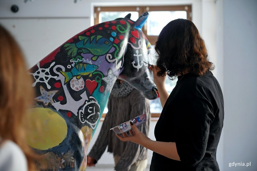 Uczennica Państwowego Liceum Sztuk Plastycznych w Gdyni malujące rzeźbę konia, kt&oacute;rą miasto przekaże na licytację WOŚP 