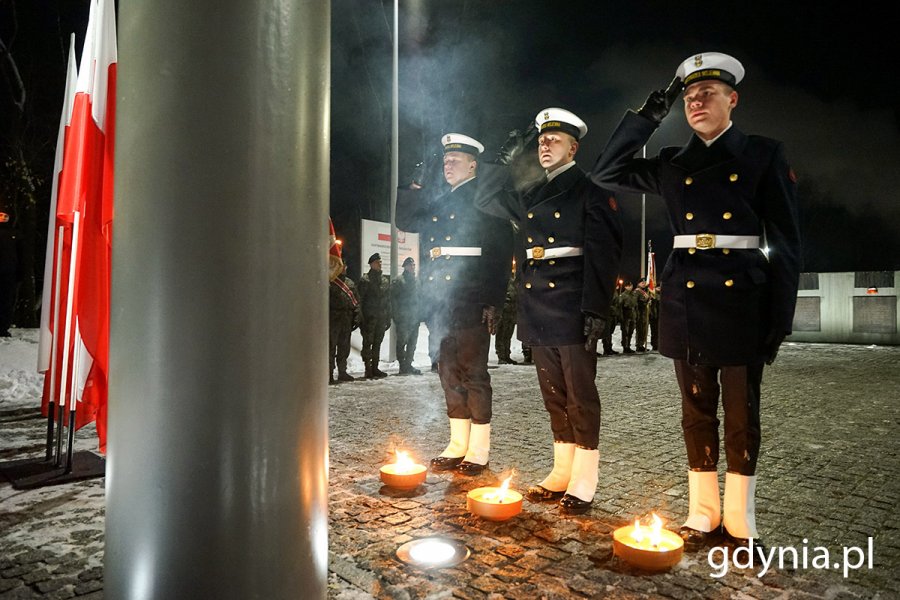 Marynarze składający znicze pamięci pod krzyżem przy Kwaterze Pamięci na cmentarzu Marynarki Wojennej 