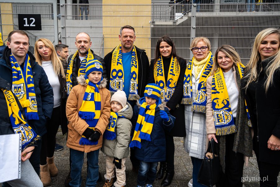 Arkadiusz i Sebastian Kupcewiczowie (w środku) pozują do zdjęcia m.in. z bliskimi i radnymi Norbertem Anisowiczem, wiceprzewodniczącą Rady Miasta Gdyni Mariolą Śrubarczyk-Cichowską, Teresą Bysewską i Moniką Strzałkowską. Symboliczne odsłonięcie tablicy z nazwą placu Janusza Kupcewicza przy Stadionie Miejskim w Gdyni (fot. Kamil Złoch)