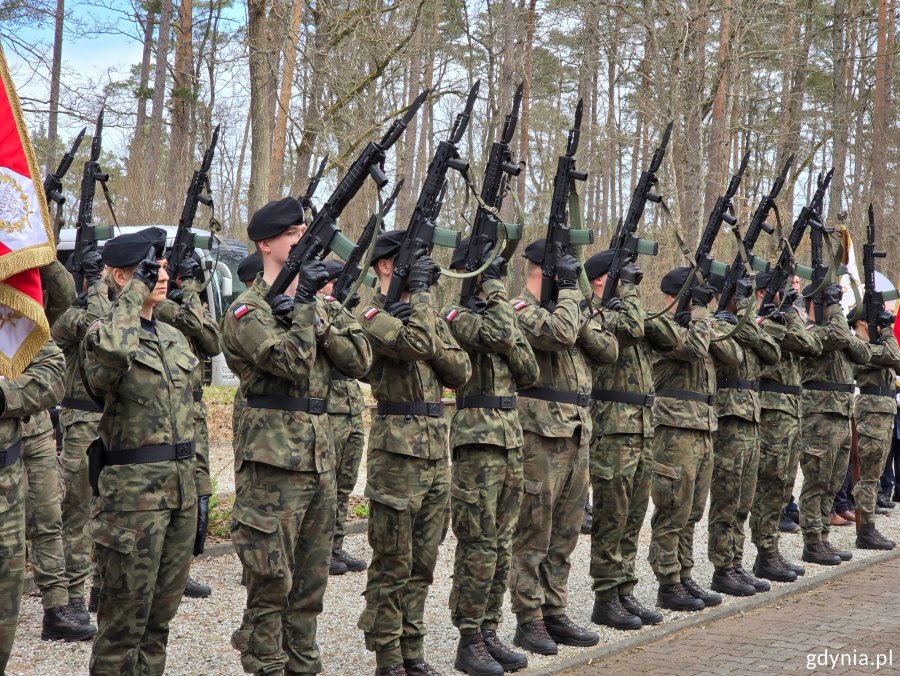 Żołnierze oddają salut bronią