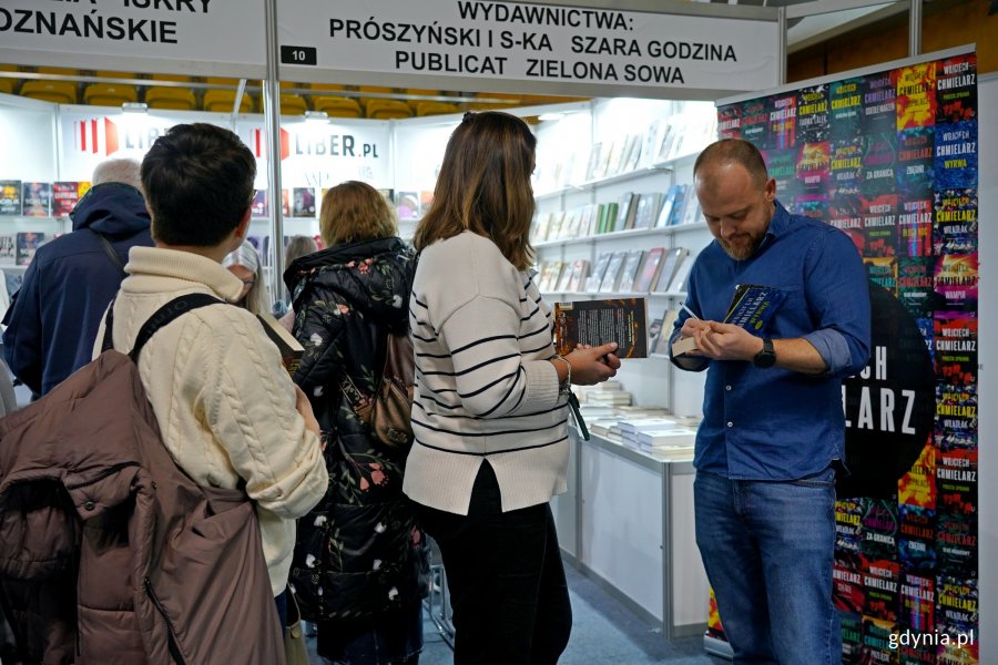 Wojciech Chmielarz wpisujący dedykacje dla czytelnik&oacute;w swoich książek 