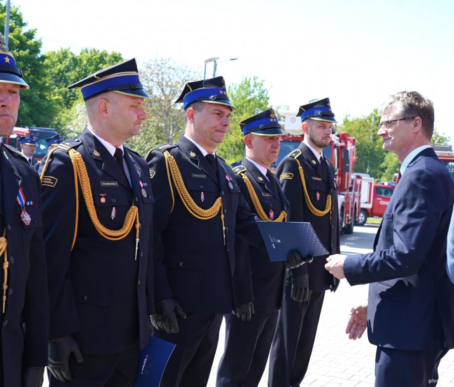 Mężczyzna w garniturze (Rafał Geremek, wiceprezydent Gdyni), podaje dłoń mężczyźnie w mundurze