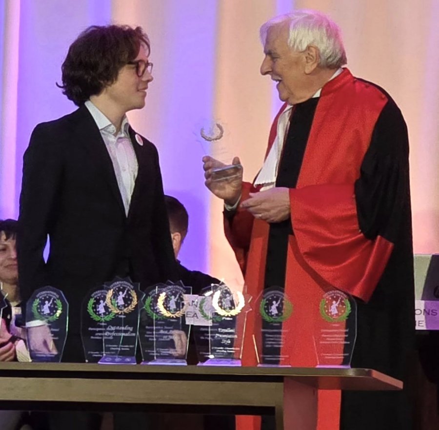 Młody człowiek odbiera nagrodę od mężczyzny w todze