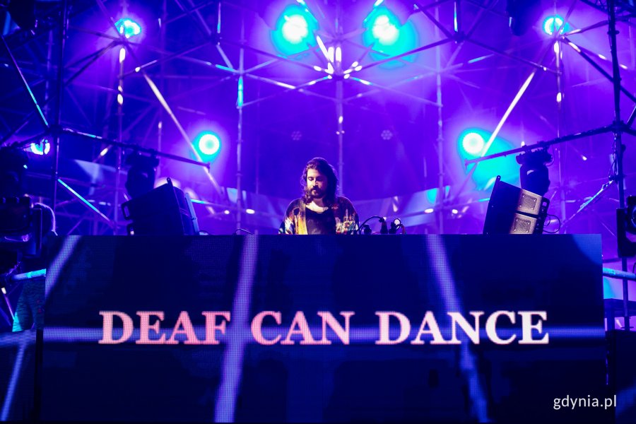 Deaf Can Dance podczas występu na Beat Stage na Open'er Festivalu 2023. Stoi za konsoletą, a wokół niego palą się niebieskie lampy // fot. Karol Stańczak