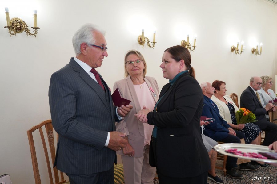 Kobieta w granatowej maryanrce rozmawia z mężczyzną w garniturze