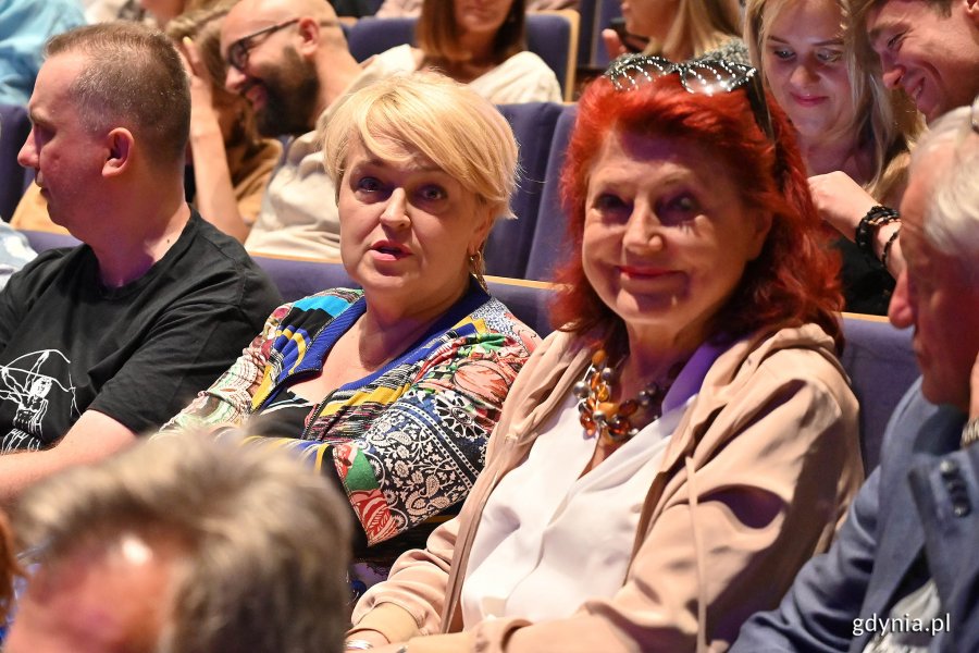 publiczność w sali teatralnej, dwie kobiety się uśmiechają