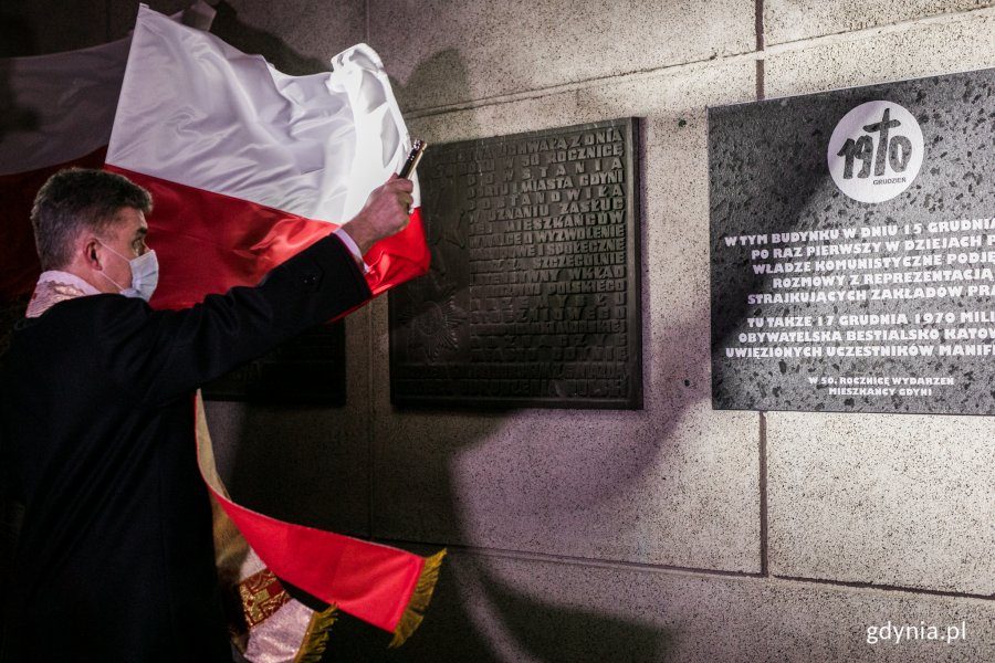 bp Zbigniew Zieliński - biskup pomocniczy archidiecezji gdańskiej święci tablicę pamiątkową na budynku gdyńskiego ratusza. W tle powiewające biało-czerwone flagi // fot. Karol Stańczak