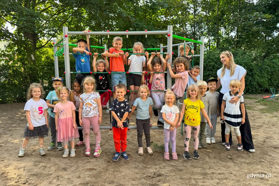 Grupa dzieci 5-letnich z nauczycielką przedszkolną na placu zabaw przy rabinkach pozuje do zdjęcia