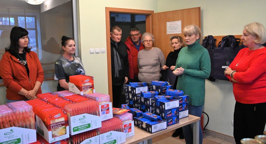 na zdjęciu uśmiechnięci wolontariusze pakują paczki