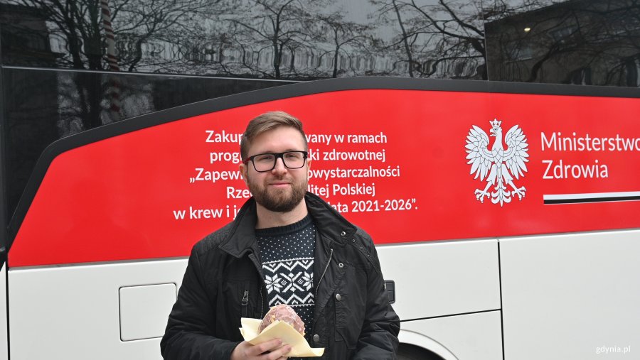 Mężczyzna z pączkiem na tle autobusu