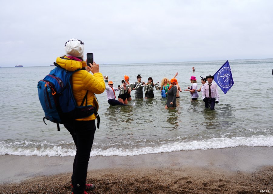 Kobieta w ż&oacute;łtej kurtce fotografuje morsy