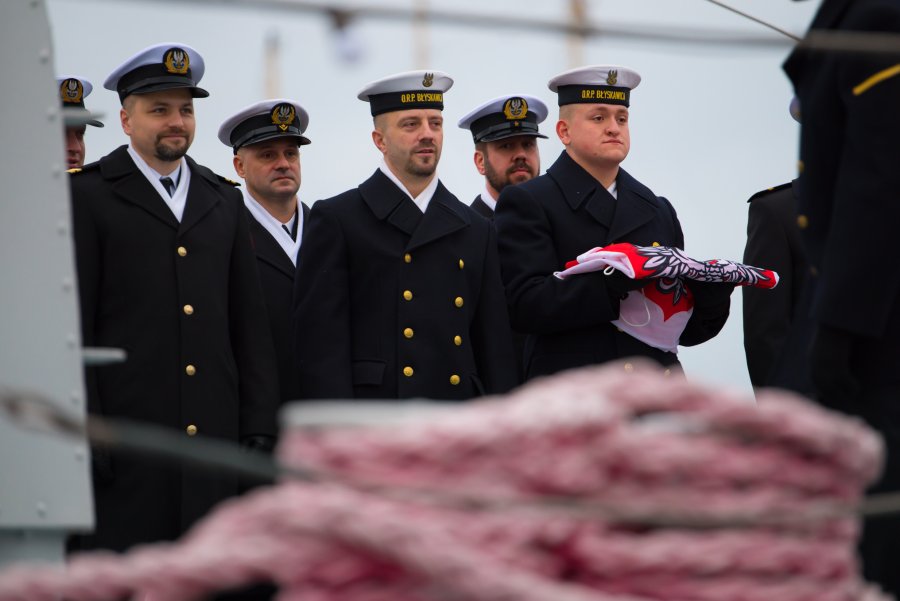 Uroczystości z okazji 84. rocznicy podniesienia bandery na okręcie ORP „Błyskawica”. Na zdjęciu 6 marynarzy w galowych mundurach. Jeden z nich trzyma w ręku złożoną biało-czerwoną banderę  // fot. bsmt Michał Pietrzak