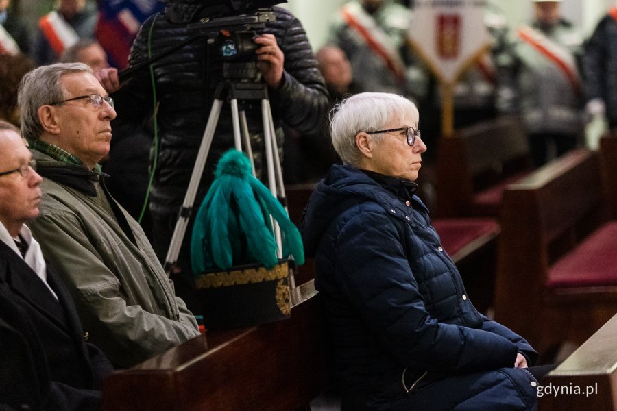 Ludzie w odświętnych strojach siedzą w kościele