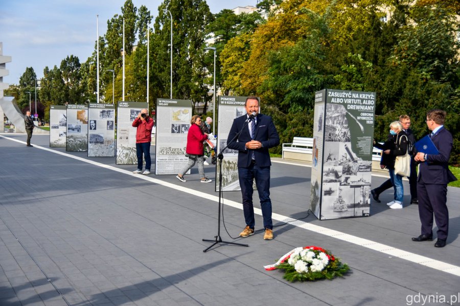 Wiceprezydent Gdyni Marek Łucyk przemawia podczas wernisażu wystawy „Zasłużyć na krzyż: albo Virtuti, albo drewniany. Obrona Wybrzeża 1939” na skwerze Kościuszki. W tle plansze, z których składa się wystawa i stojący przy nich mieszkańcy // fot. Paweł Kukla