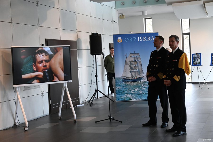 Dwaj mężczyźni w mundurach, w tle fotografie