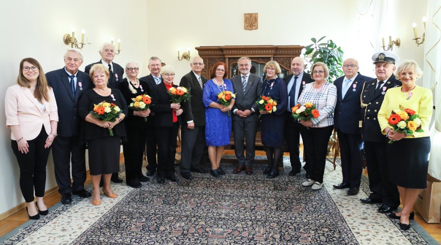 na zdjęciu seniorzy stojący z prezydentem w odświętnej sali 