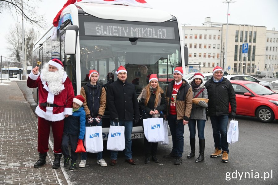 Mikołaj i jego pomocnicy przy autobusie z napisem: święty Mikołaj