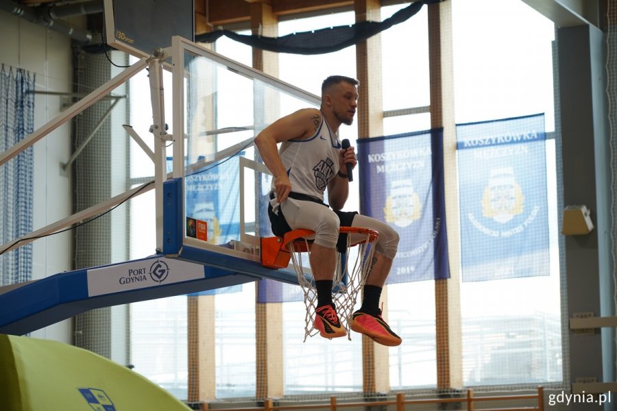 Prowadzący mikołajki Kacper „Kacpa” Lachowicz siedzi na koszu