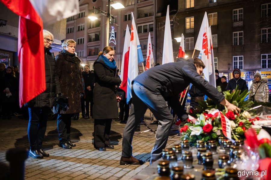 Mężczyzna składający kwiaty przed pomnikiem